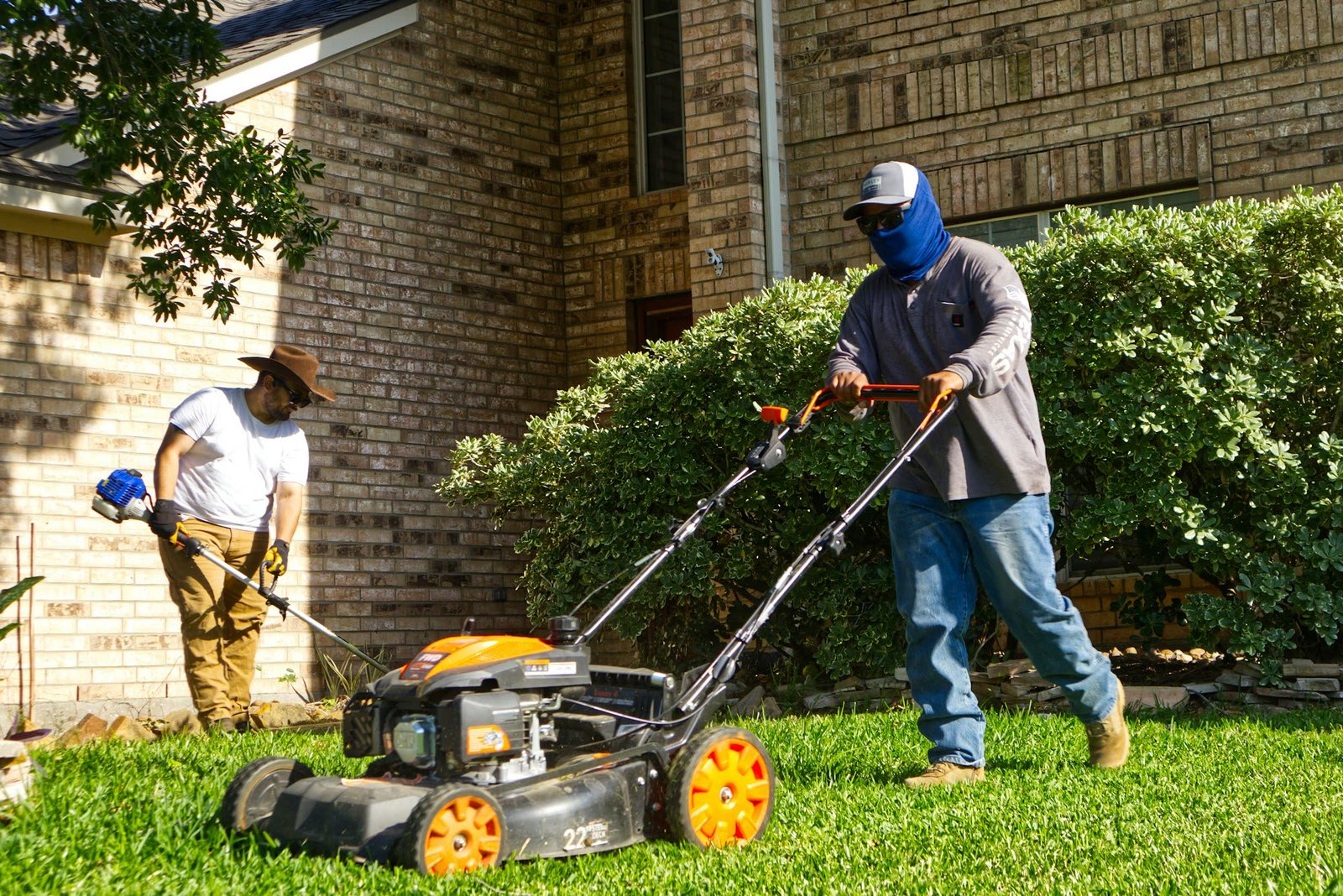 Two-person crew mowing and edge-trimming a residential lawn